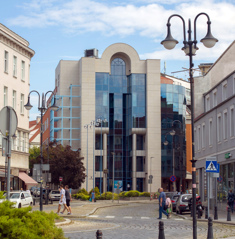 postmodernistyczna kamienica ze szkła i kamienica z łukiem na szczycie