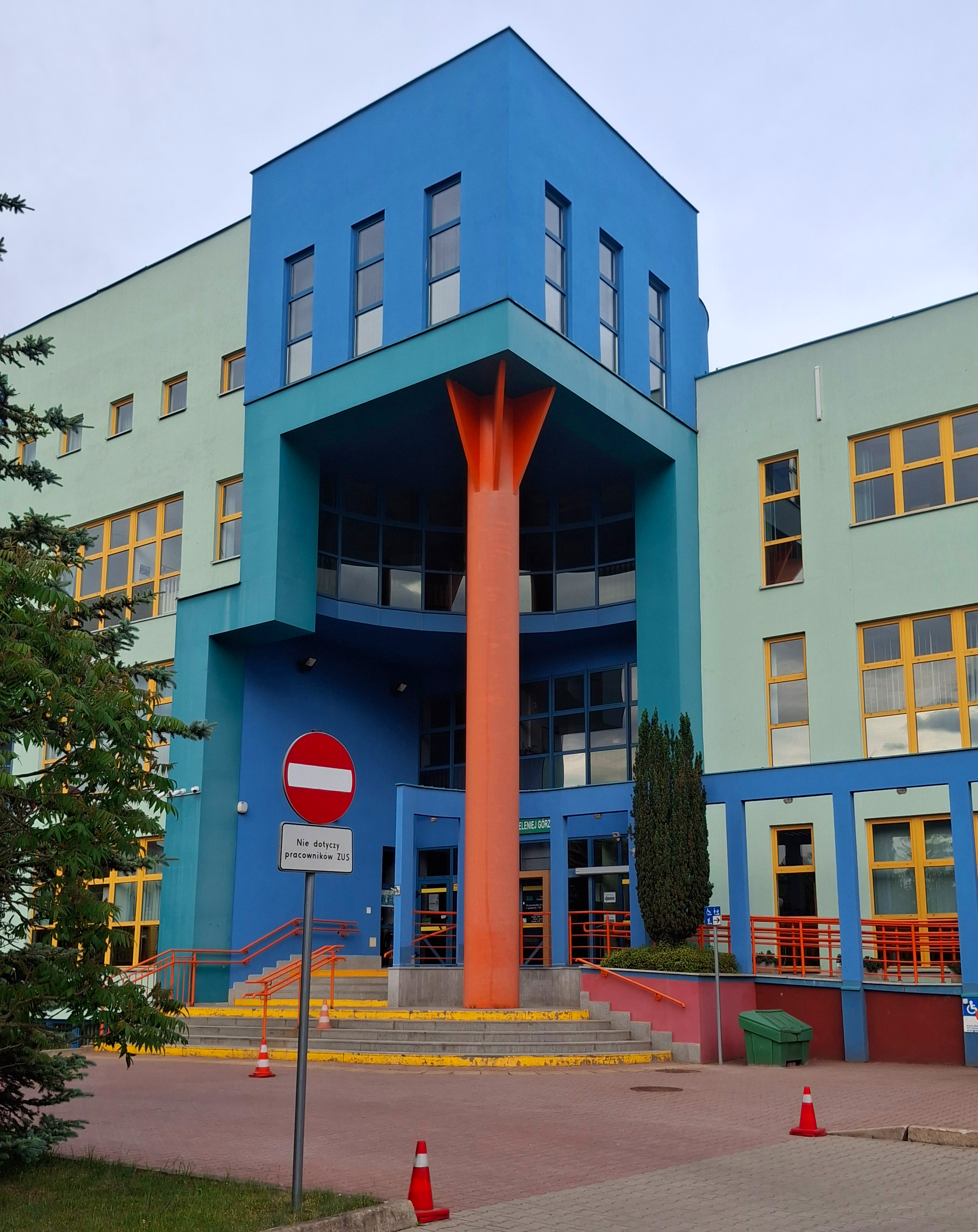 Wycięty narożnik kolorowego budynku podparty pomarańczową kolumną